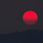 A captivating blood moon rising over a silhouette of hills, capturing the beauty of twilight.