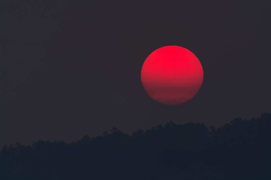 A captivating blood moon rising over a silhouette of hills, capturing the beauty of twilight.