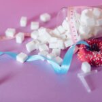 Creative representation of sugar consumption using cubes, donut, ribbon, and syringe.