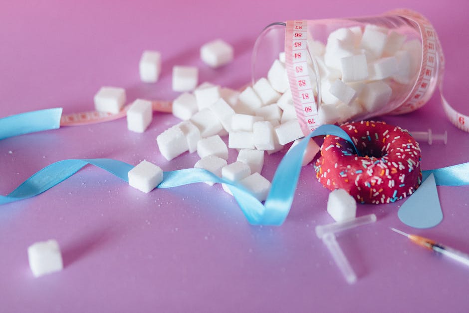 Creative representation of sugar consumption using cubes, donut, ribbon, and syringe.