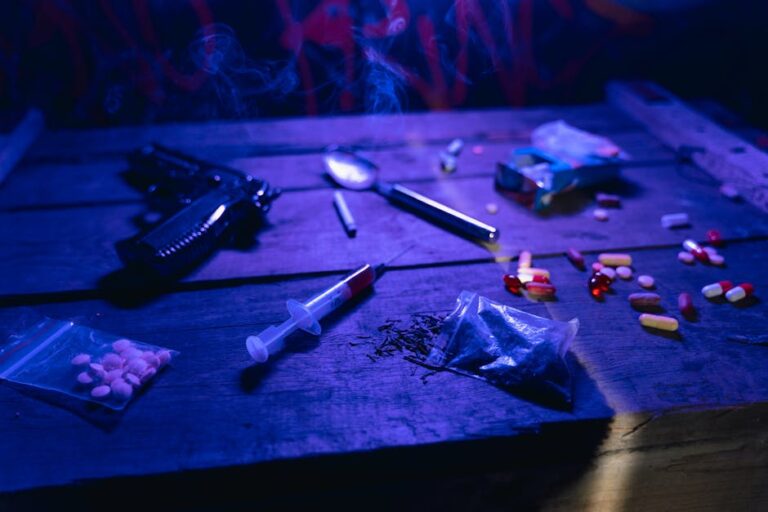 A moody scene displaying drugs, a gun, and smoke under dramatic lighting.