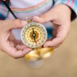A detailed view of hands holding a vintage compass, suggesting exploration and guidance.