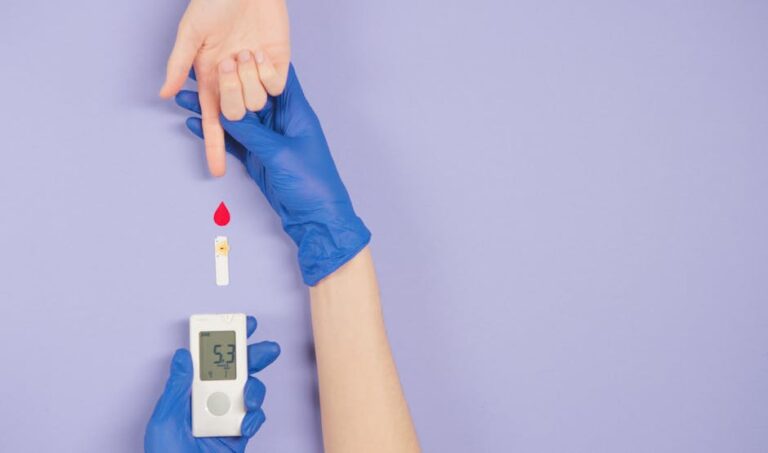 Gloved hand testing blood glucose level with meter and blood drop.