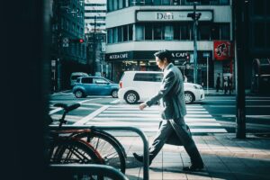 Businessman in suit crossing street in vibrant city setting.