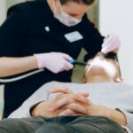 Patient receiving dental care from a dentist wearing gloves and mask in a clinic.