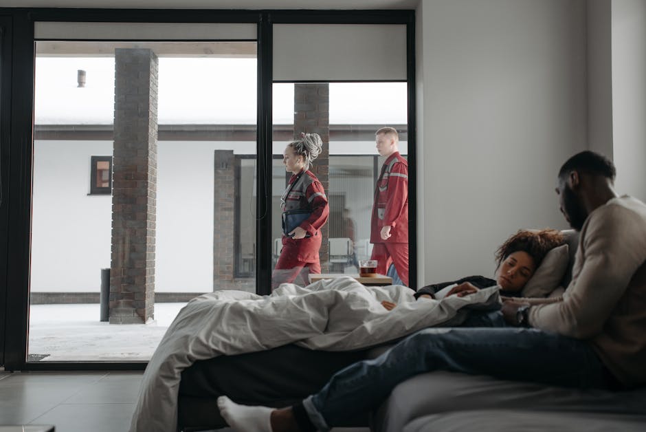 Paramedics assist a woman at home while her partner comforts her, emphasizing healthcare support.