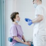 Healthcare worker performs a COVID-19 swab test on a seated patient indoors.