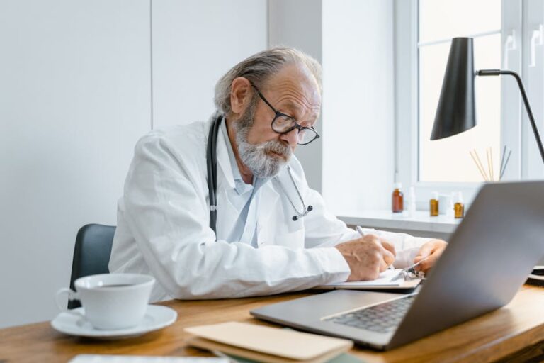 Experienced senior doctor writes a prescription online in a bright, modern office.
