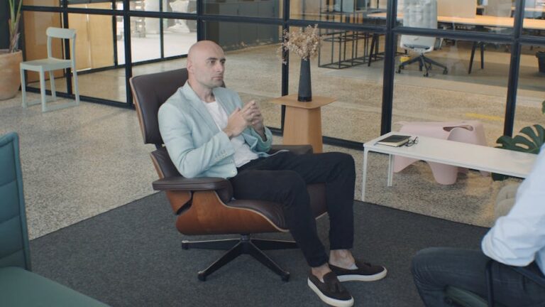Bald man engaged in a professional consultation sitting in a modern, well-lit office.