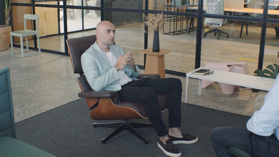 Bald man engaged in a professional consultation sitting in a modern, well-lit office.