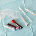 Top view of empty and full of blood vials and plastic syringes and eyeglasses placed on medical diaper