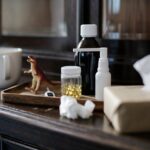 Indoor scene featuring medicines, a tea cup, tissues, and a toy dinosaur for a cozy treatment ambiance.