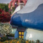 Charming mushroom house surrounded by colorful blooming flowers in a vibrant garden setting.