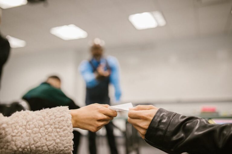 Focused hands exchanging paper in a classroom environment indicating discreet communication.