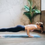 Woman in active wear doing yoga push-up on mat indoors, embracing healthy lifestyle.