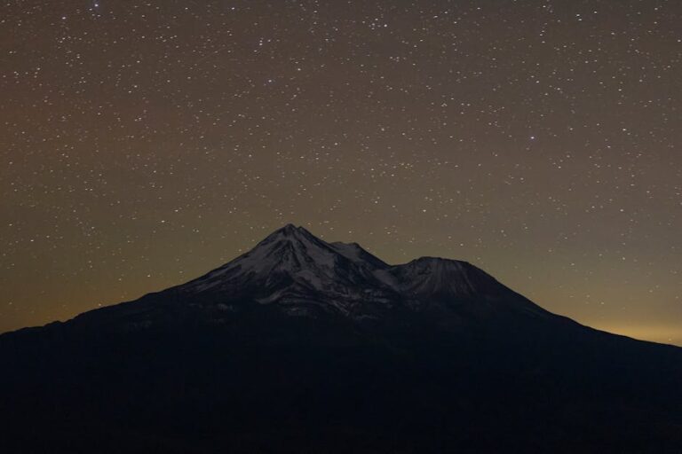 Captivating view of a star-filled sky over a snow-capped mountain at night.