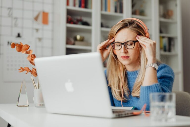 A woman experiencing stress while working on a laptop in a home office setting, highlighting a work-from-home lifestyle.