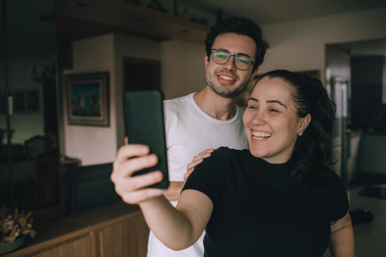 Smiling couple taking a selfie inside their home, enjoying a joyful moment together.