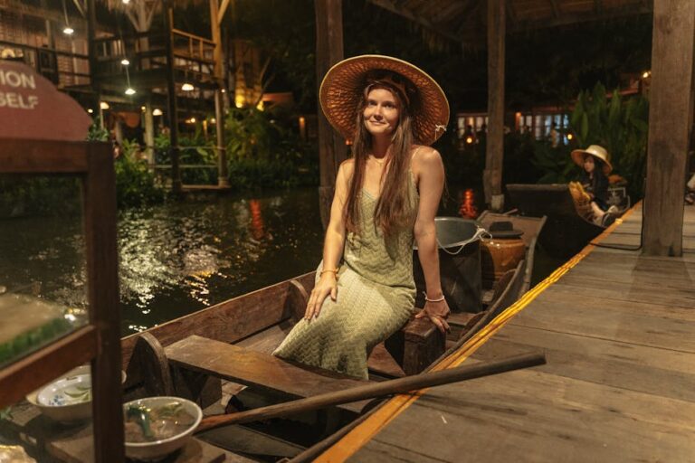Smiling woman in a straw hat sitting on a boat at night in Phuket, Thailand.