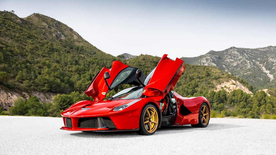 A striking red sports car with open doors against a serene mountain backdrop.