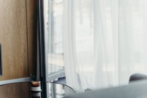 A modern hotel room with sheer curtains softly lit, emphasizing luxury and tranquility.