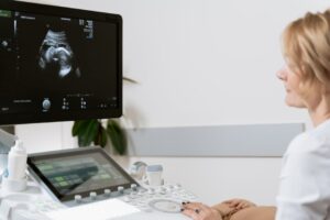 A woman undergoing an ultrasound scan by a healthcare professional.
