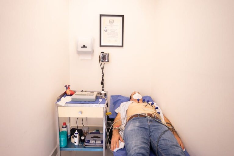 Patient lying down for an electrocardiogram in a clinic room wearing a face mask.