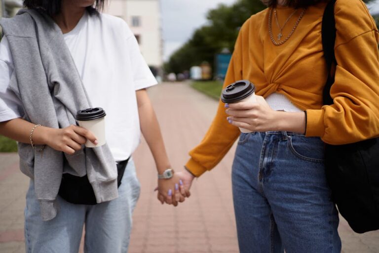 Two people holding hands and enjoying coffee on a casual outdoor walk.