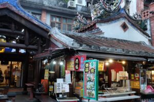 Vibrant street food market with traditional architecture in an Asian city.