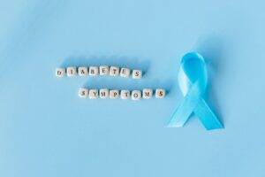 Conceptual image emphasizing diabetes symptoms with a blue awareness ribbon and letter dice.