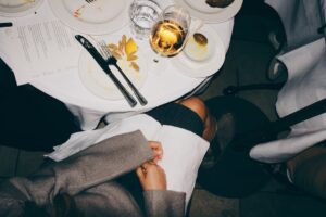 A top-down view of a dining table with elegant table setting and a glass of white wine.